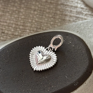 S925 sterling silver heart pendant with sunburst texture detail on stone background