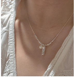 Detail of S925 silver necklace with pearl and irregular pendant on a female model