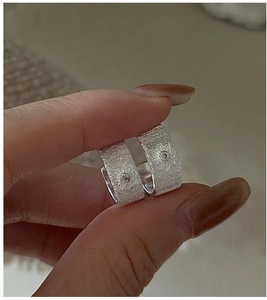 Detail of S925 sterling silver hoop earrings with brushed texture and floral zircon inlay