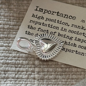 Vintage S925 silver heart pendant with sunburst texture and lobster clasp on rustic fabric