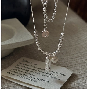Close-up of S925 sterling silver necklace featuring pearl and hammered cylinder pendant