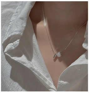 Detail of S925 silver necklace featuring a polished metal cylinder and a white pearl