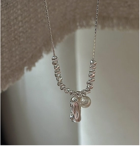Macro view of S925 sterling silver necklace with textured beads and a hanging pearl