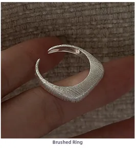Close-up of minimalist S925 sterling silver ring with brushed texture and open band design