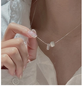 Detailed view of silver necklace with brushed cylinder pendant and translucent bead