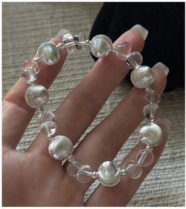 Detail eines Perlenarmbands mit klaren Glasperlen und silbernen gebürsteten Texturelementen
