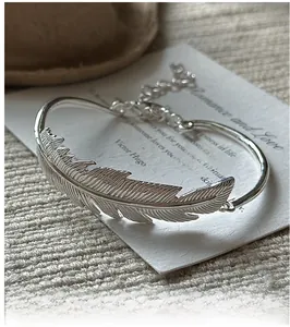 Detailed macro view of S925 silver feather bangle with adjustable chain and intricate texture