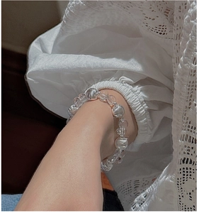 Nahaufnahme eines klaren Kristallperlenarmbands am Handgelenk mit eleganter Spitze