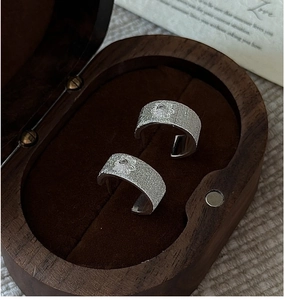 Macro detail of silver earrings with floral relief on a vintage wooden jewelry gift box