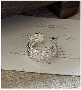 Macro shot of S925 sterling silver ring showing intricate handmade woven texture on paper