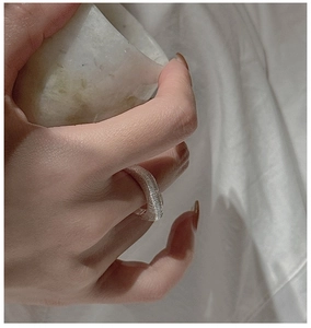 Macro detail of silver ring with brushed texture on hand over white fabric