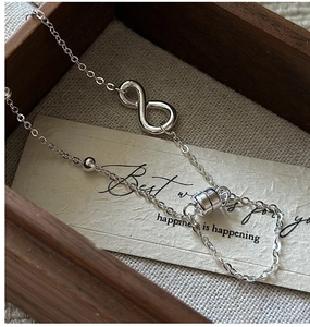 Detail of S925 silver infinity bracelet with magnetic clasp on a beige paper background