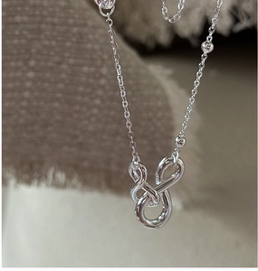 Detail of silver S925 necklace with twisted knot pendant and beaded chain design