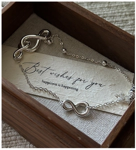 Macro shot of silver infinity symbol bracelet on a gift card inside a wooden jewelry box