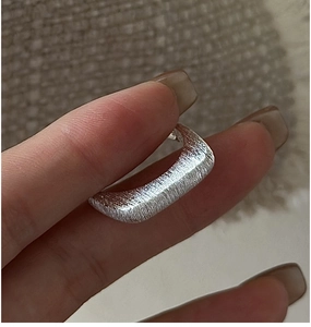 Macro shot of silver S925 minimalist wide band ring with refined brushed metal texture