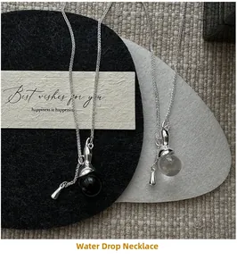 Detailed view of silver water drop pendants on minimalist chains over a gift card