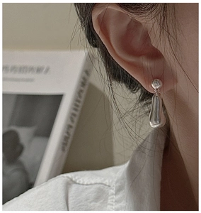 Close-up of minimalist S925 sterling silver teardrop earrings on a model’s ear