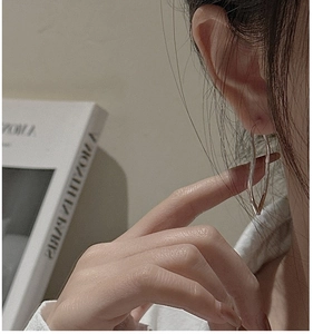 Close-up of S925 sterling silver wavy hoop earring on model with elegant styling