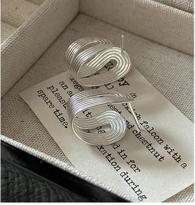 Macro detail of S925 sterling silver earrings with wavy texture and brushed finish