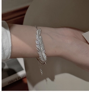 Detailed view of an adjustable silver feather bracelet with intricate texture and chain