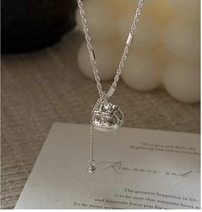 Detailed view of silver persimmon tassel necklace with twisted rope chain on lifestyle background
