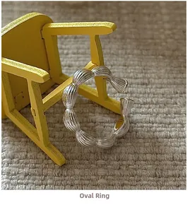 Detail of S925 silver oval ring with shell texture on a miniature yellow chair