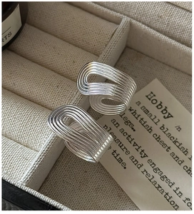 Detailed view of two stacked S925 silver rings with wavy texture in a jewelry box