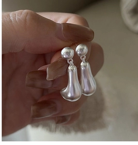 Detail view of silver drop earrings with smooth matte finish and irregular liquid waterdrop shape