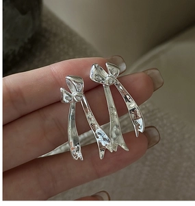 Close-up of S925 sterling silver bow earrings featuring a delicate pleated texture design