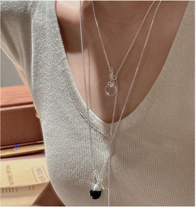 Detail of layered S925 silver necklace with white crystal and black ball on a model