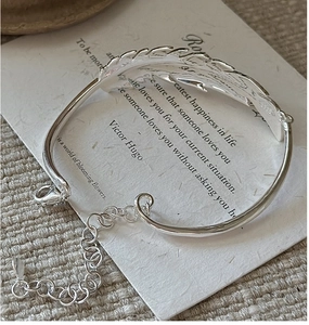 Close-up of S925 sterling silver feather bracelet with lobster clasp and texture details