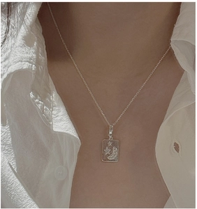Close-up of a silver vintage star and moon pendant necklace worn on a white shirt