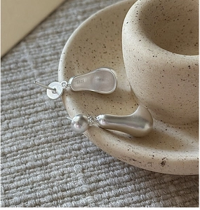 Detail of matte S925 sterling silver earrings with irregular water drop design and hallmark