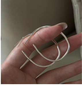 Detailed close-up of large S925 sterling silver hoop earrings with irregular streamline design