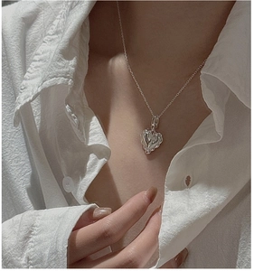 Close-up of a vintage embossed silver heart pendant on a delicate chain necklace