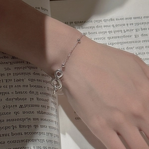 Minimalist S925 sterling silver infinity symbol bracelet worn on wrist over a book