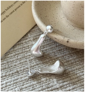 Macro detail of matte S925 sterling silver teardrop earrings on minimalist fabric