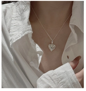 Macro detail of a vintage-textured S925 sterling silver heart pendant on a thin neck chain