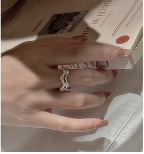 Detailaufnahme des silbernen Wellenrings mit Matt-Finish an der Hand am Buch