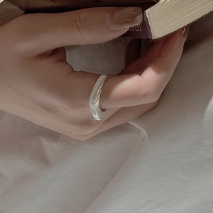 S925 sterling silver ring with handmade hammer texture shown on a hand turning book pages