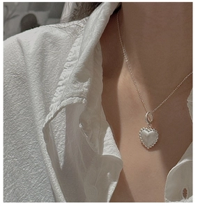Detail of S925 sterling silver heart pendant with vintage texture on a thin chain