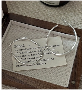 Close-up of S925 sterling silver hoop earrings with wavy texture in a vintage wooden box