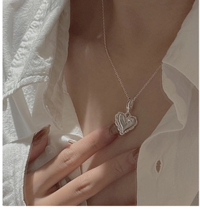 Detail shot of a layered heart-shaped silver pendant on a delicate chain necklace