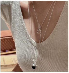 Detail of layered S925 silver necklaces with clear teardrop and black sphere pendants