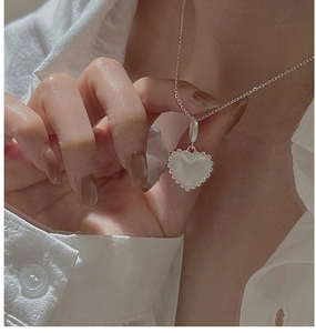 Detail of vintage heart pendant with vertical texture on white shirt background