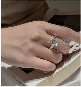 Detail of 925 silver ring with clear round-cut crystal shown on hand with magazine