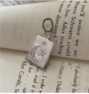 Detailed close-up of a S925 sterling silver moon and star charm pendant on a book