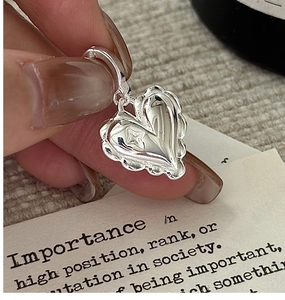 Detailed close-up of S925 sterling silver heart pendant with star relief and wavy edges