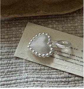 Macro detail of S925 sterling silver heart pendant with brushed texture and beaded edge