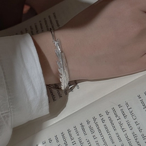 Artistic S925 sterling silver feather cuff bracelet on a vintage book backdrop